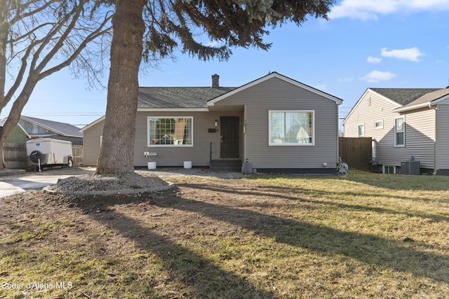 view of front of property featuring central air condition unit, a chimney, a front yard, and fence