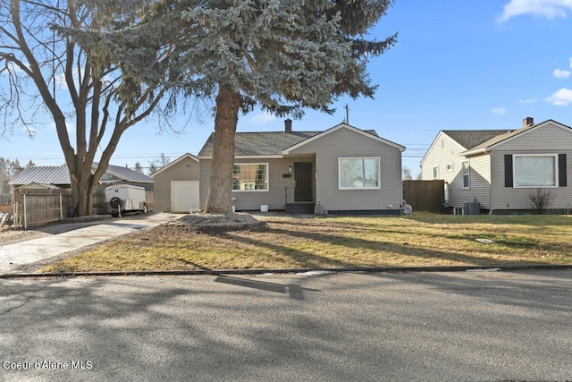 view of front of house featuring a front lawn, driveway, fence, cooling unit, and a garage