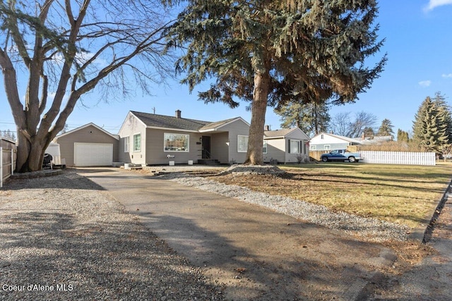 single story home with a detached garage, fence, a front yard, an outbuilding, and driveway