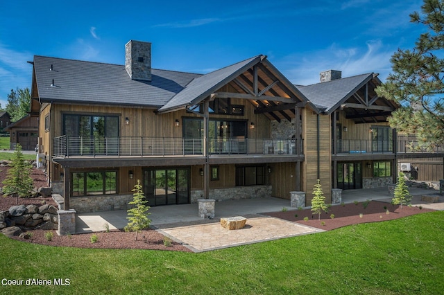 back of property featuring stone siding, a chimney, and a patio area