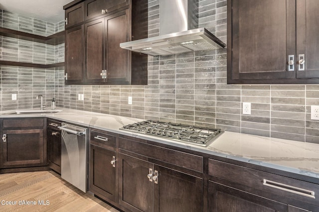 kitchen featuring stainless steel appliances, dark brown cabinets, wall chimney exhaust hood, and light stone countertops