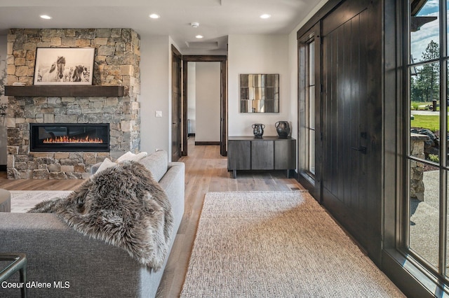 interior space with recessed lighting, a stone fireplace, and light wood-style flooring