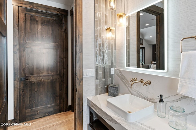 bathroom with wood finished floors, tile walls, and vanity