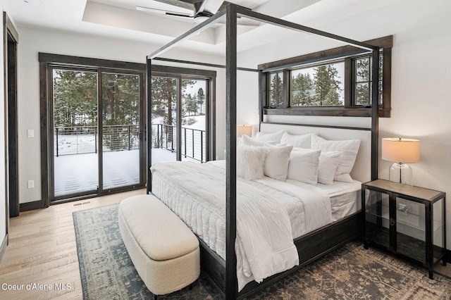 bedroom with access to outside, multiple windows, visible vents, and wood finished floors