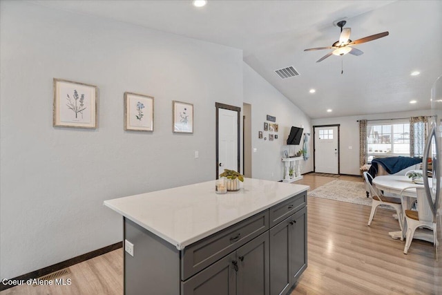 kitchen featuring a center island, light countertops, visible vents, open floor plan, and vaulted ceiling