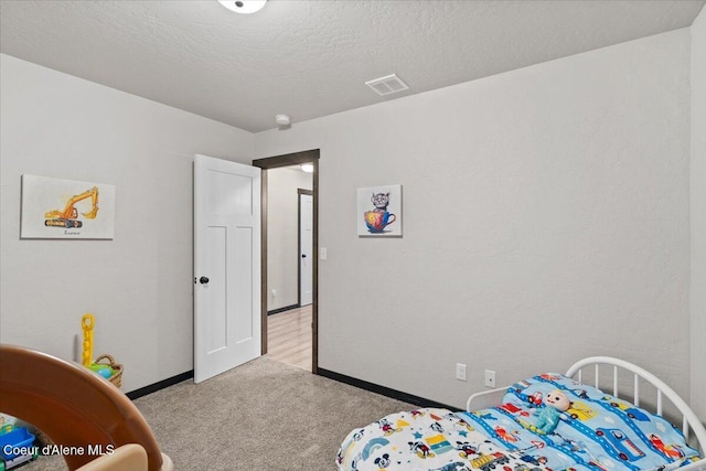 bedroom featuring a textured ceiling, baseboards, visible vents, and light colored carpet