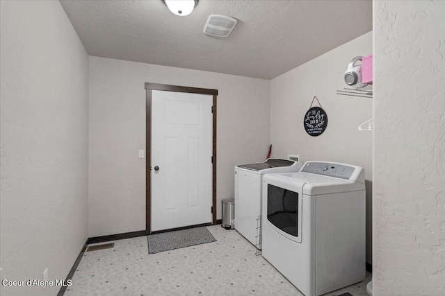 washroom featuring a textured ceiling, washing machine and dryer, laundry area, visible vents, and light floors