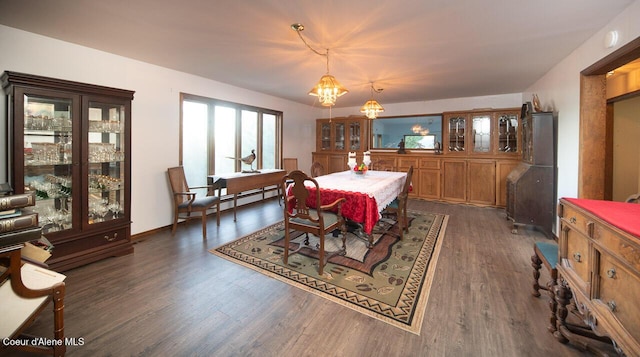 dining space with dark wood-style floors and an inviting chandelier