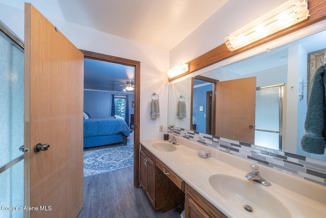 ensuite bathroom with ensuite bath, tasteful backsplash, a sink, and wood finished floors