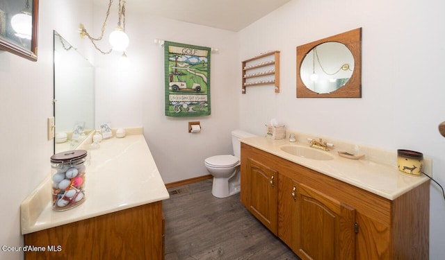 bathroom featuring toilet, wood finished floors, vanity, and baseboards