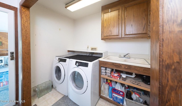 clothes washing area with separate washer and dryer, a sink, and cabinet space