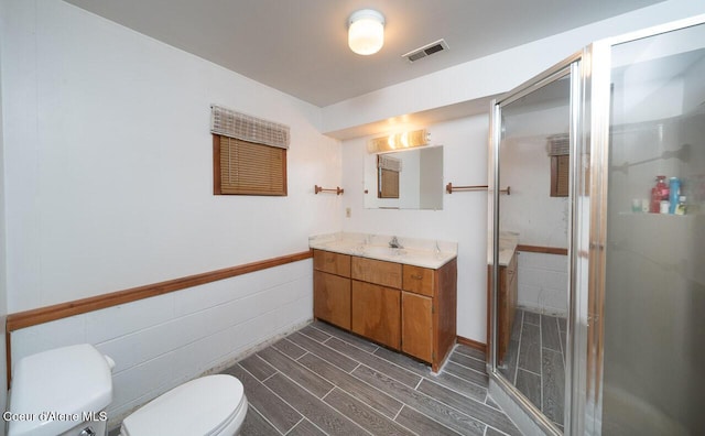 bathroom with visible vents, toilet, a stall shower, wood tiled floor, and vanity