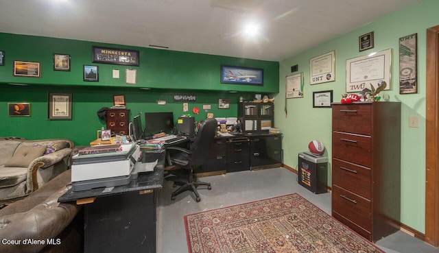 home office featuring concrete floors and baseboards