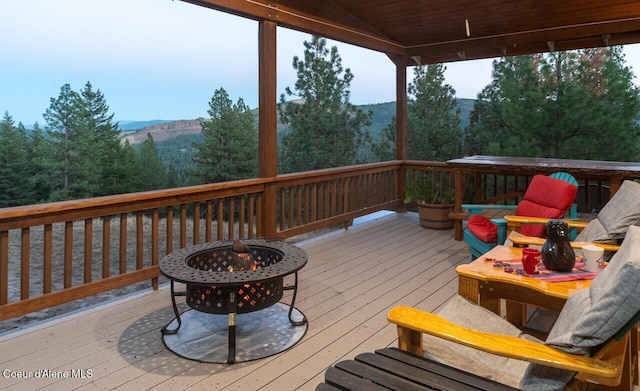 wooden terrace with a fire pit, a wooded view, and a mountain view