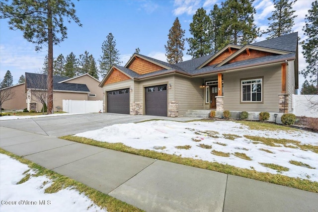 craftsman-style house with a garage, stone siding, fence, and driveway