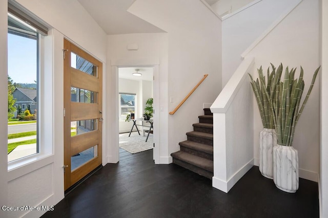 foyer entrance with dark wood-style floors, stairs, and baseboards