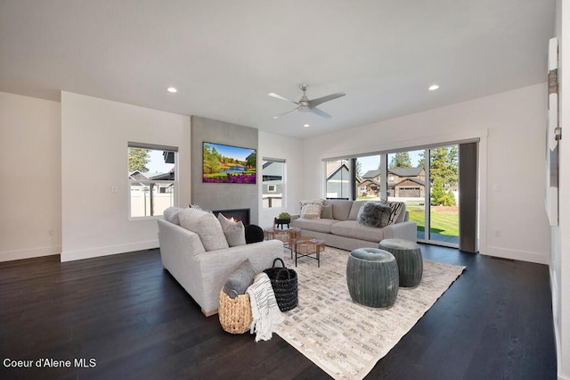 living room with a warm lit fireplace, a wealth of natural light, and recessed lighting