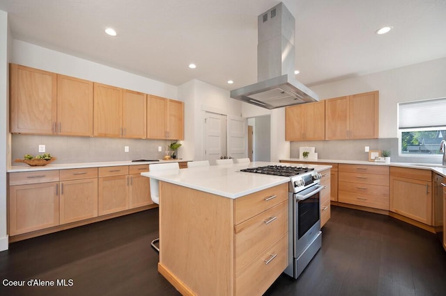 kitchen with stainless steel gas range oven, light brown cabinets, a kitchen island, light countertops, and island exhaust hood