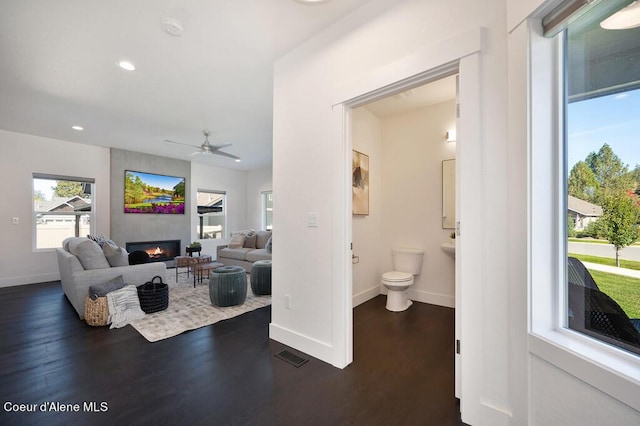 living room with visible vents, baseboards, dark wood-style flooring, a fireplace, and recessed lighting