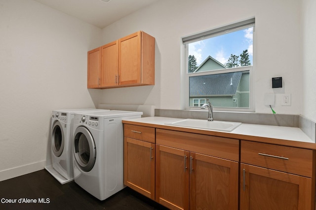 laundry area featuring cabinet space, baseboards, washer and dryer, and a sink