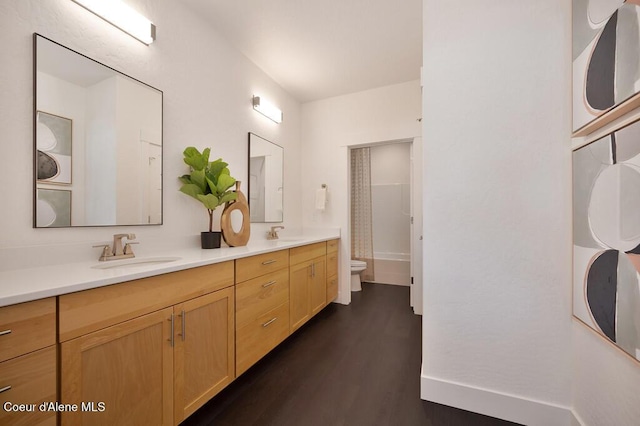 full bath featuring shower / bath combination, double vanity, toilet, wood finished floors, and a sink