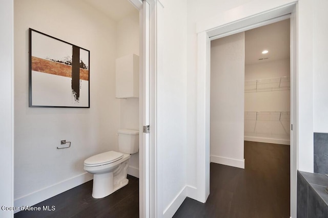 bathroom with toilet, baseboards, and wood finished floors