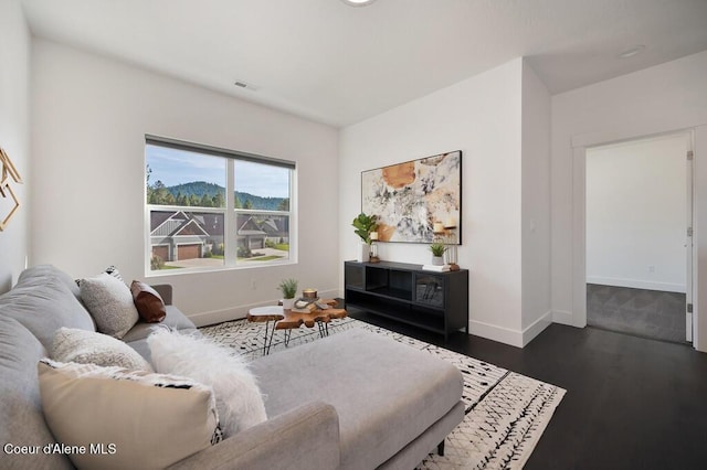 living area with dark wood-style floors, visible vents, and baseboards