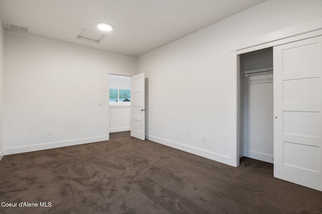 unfurnished bedroom featuring visible vents, a closet, dark carpet, and baseboards