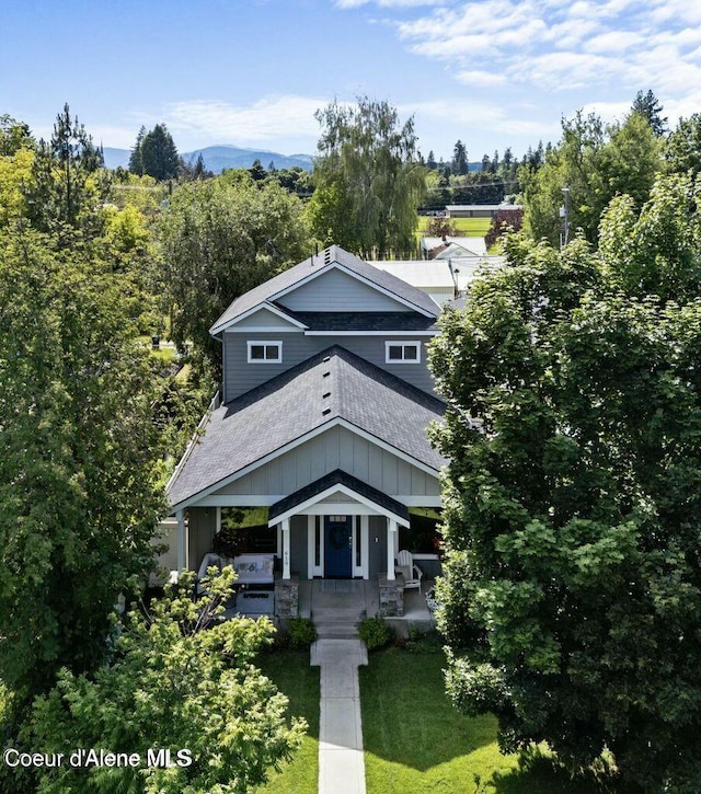 view of front facade featuring a shingled roof and a front lawn