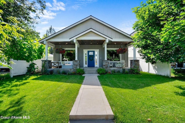 view of front of property with a porch, board and batten siding, a front lawn, and fence