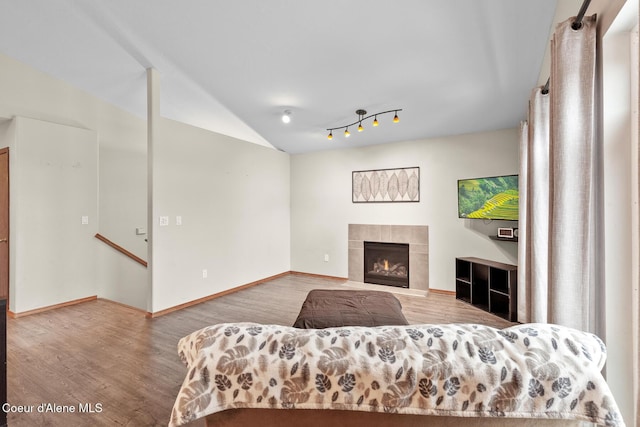 living room with lofted ceiling, a fireplace, wood finished floors, and baseboards