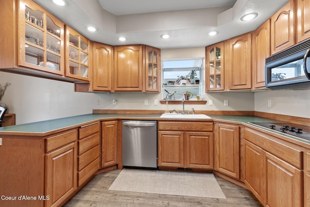 kitchen featuring a sink, light wood-type flooring, black appliances, brown cabinetry, and glass insert cabinets