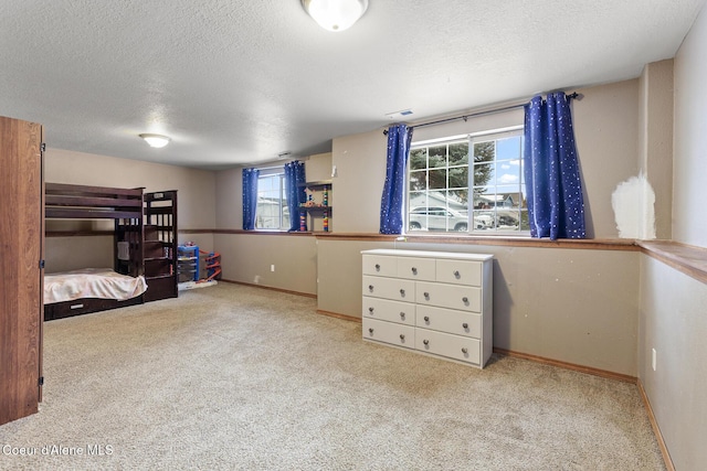 bedroom with light colored carpet, a textured ceiling, and baseboards