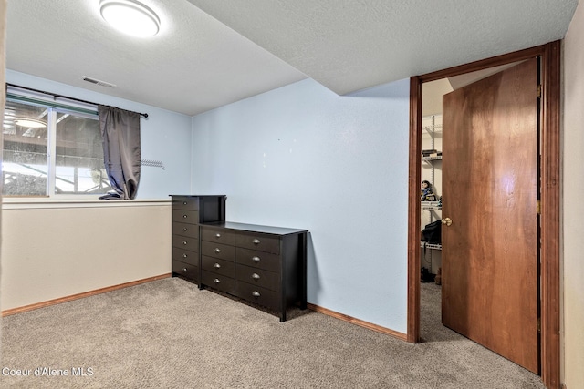 bedroom featuring visible vents, light colored carpet, a textured ceiling, and baseboards