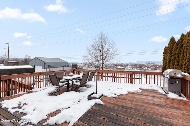 snow covered deck featuring a garage, outdoor dining space, and grilling area