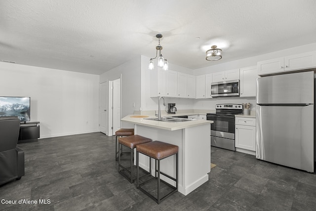 kitchen featuring appliances with stainless steel finishes, white cabinets, light countertops, and decorative light fixtures