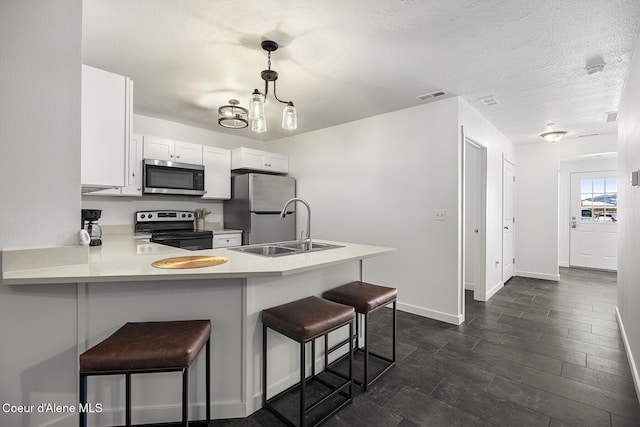 kitchen featuring a peninsula, visible vents, a kitchen breakfast bar, light countertops, and appliances with stainless steel finishes