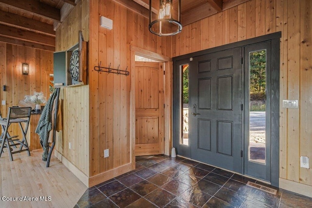 entrance foyer with wood walls, plenty of natural light, and beam ceiling