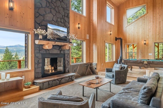 living area featuring high vaulted ceiling, a stone fireplace, billiards, and wooden walls