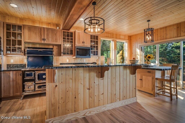 kitchen with black microwave, light wood finished floors, wood ceiling, and wooden walls