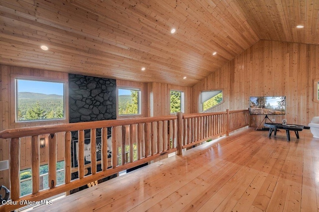 interior space with lofted ceiling, wooden ceiling, hardwood / wood-style flooring, a mountain view, and wooden walls