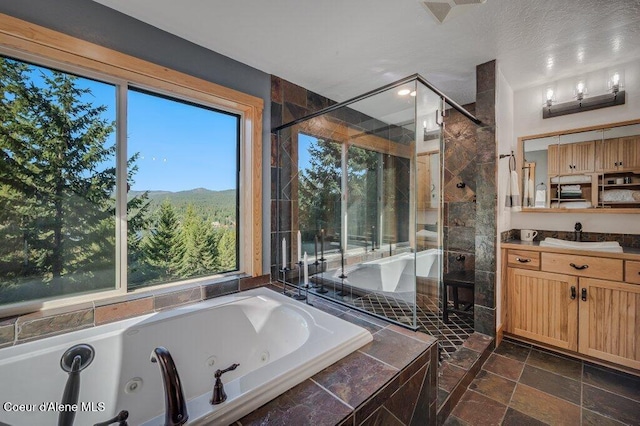 bathroom featuring a mountain view, vanity, a jetted tub, a shower stall, and stone finish floor