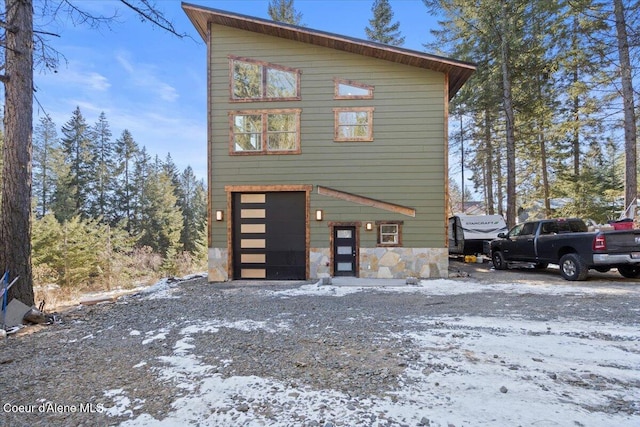 view of front of property featuring a garage and stone siding