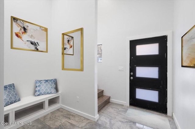 foyer with marble finish floor, stairway, and baseboards