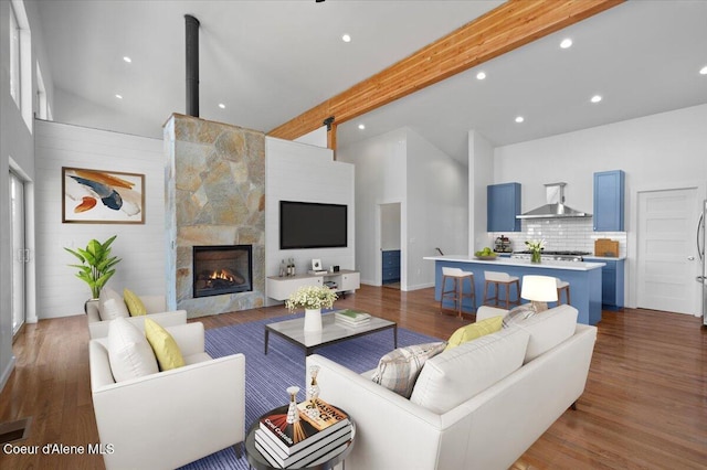 living area featuring high vaulted ceiling, beam ceiling, dark wood finished floors, and a stone fireplace