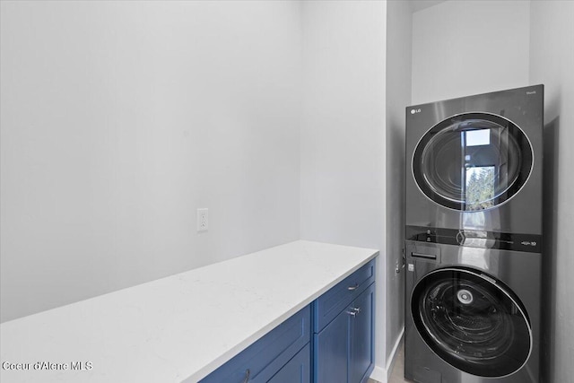 laundry area featuring stacked washer and dryer and cabinet space