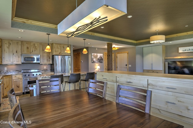 kitchen featuring a breakfast bar area, recessed lighting, a raised ceiling, appliances with stainless steel finishes, and light stone countertops