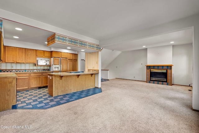 kitchen featuring white microwave, a breakfast bar area, paneled built in fridge, open floor plan, and light countertops