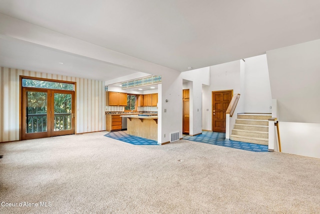 unfurnished living room featuring light carpet, visible vents, and stairway