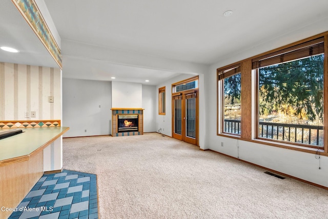 unfurnished living room with carpet, recessed lighting, visible vents, a tile fireplace, and baseboards